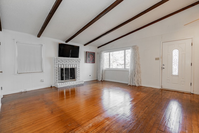 unfurnished living room with lofted ceiling with beams, dark hardwood / wood-style floors, and a brick fireplace