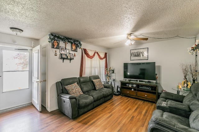 living room featuring ceiling fan, hardwood / wood-style floors, and a textured ceiling