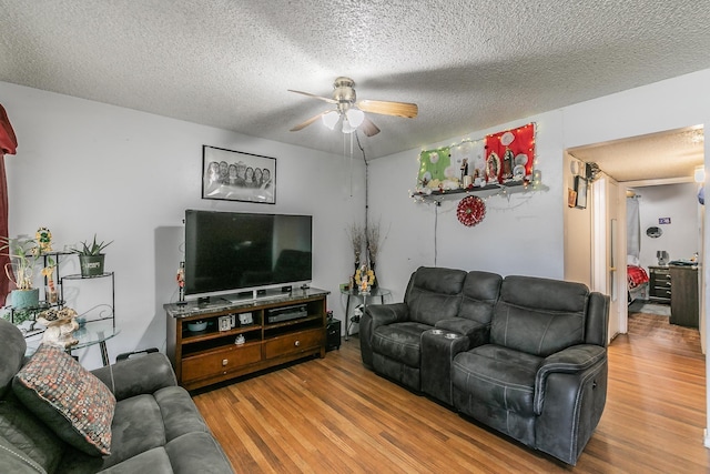 living room with hardwood / wood-style flooring, ceiling fan, and a textured ceiling