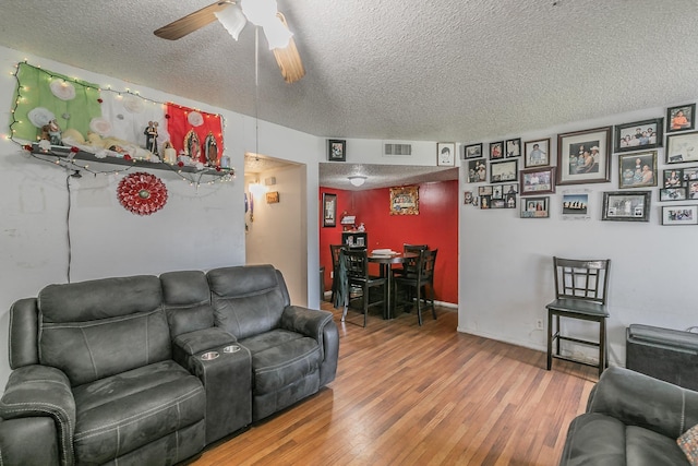 living room with ceiling fan, a textured ceiling, and hardwood / wood-style floors