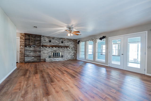 unfurnished living room featuring ceiling fan, french doors, a brick fireplace, and wood-type flooring