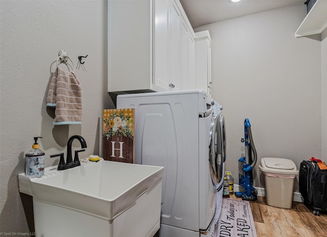 washroom with cabinets, washer and clothes dryer, sink, and light wood-type flooring