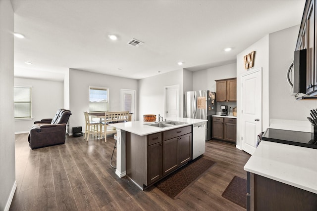 kitchen featuring dark brown cabinets, sink, dark hardwood / wood-style floors, an island with sink, and stainless steel appliances