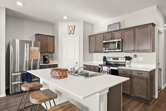 kitchen featuring a kitchen breakfast bar, sink, dark wood-type flooring, an island with sink, and stainless steel appliances