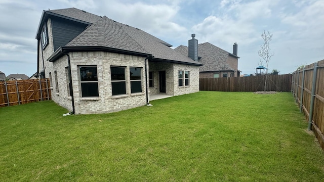 back of house with a patio area and a lawn