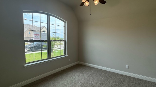 empty room featuring ceiling fan, vaulted ceiling, and carpet