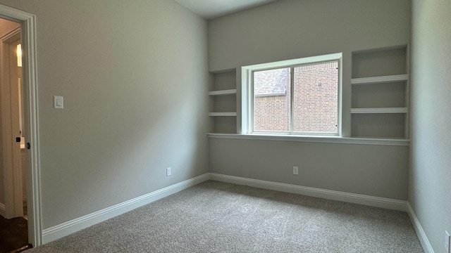 carpeted spare room featuring built in shelves