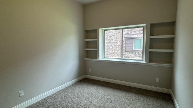 carpeted spare room with built in shelves