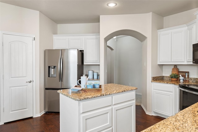 kitchen with appliances with stainless steel finishes, a center island, white cabinets, and light stone countertops