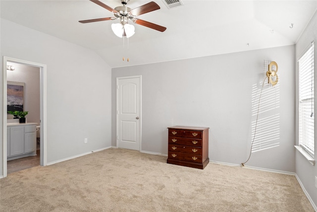 unfurnished bedroom featuring light colored carpet, lofted ceiling, connected bathroom, and multiple windows