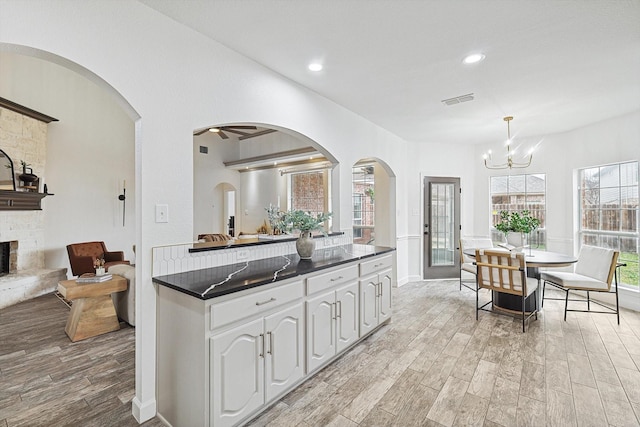 kitchen featuring dark countertops, light wood-style floors, white cabinets, and hanging light fixtures