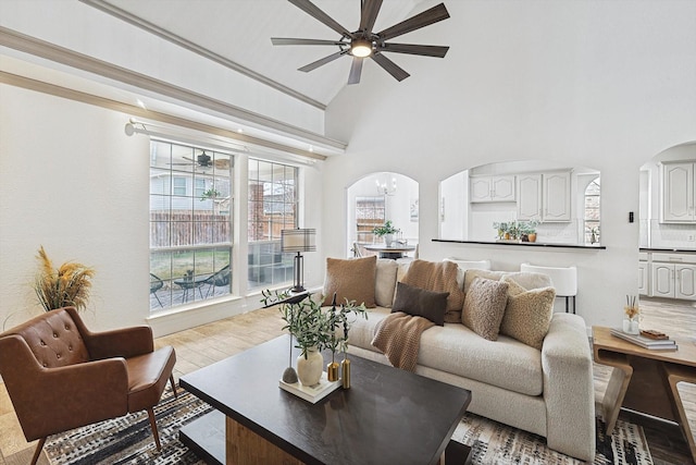 living room with a towering ceiling, arched walkways, and ceiling fan with notable chandelier