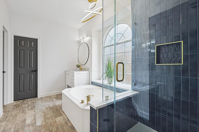 bathroom with wood finished floors, a stall shower, a garden tub, and vanity