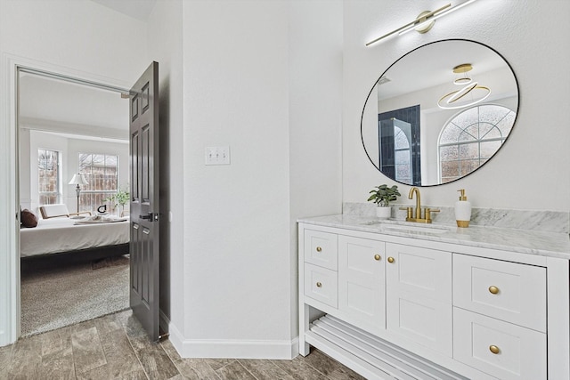 ensuite bathroom with vanity, baseboards, wood finish floors, and ensuite bathroom