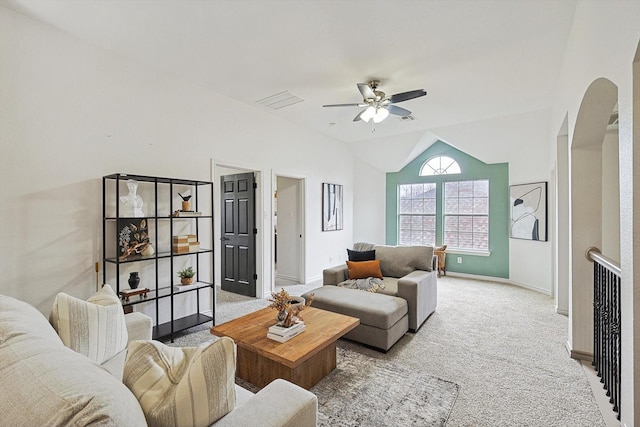 living room with lofted ceiling, light colored carpet, arched walkways, and baseboards