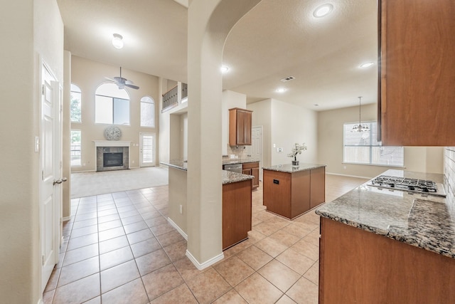 kitchen with ceiling fan, a center island, stainless steel appliances, and dark stone countertops