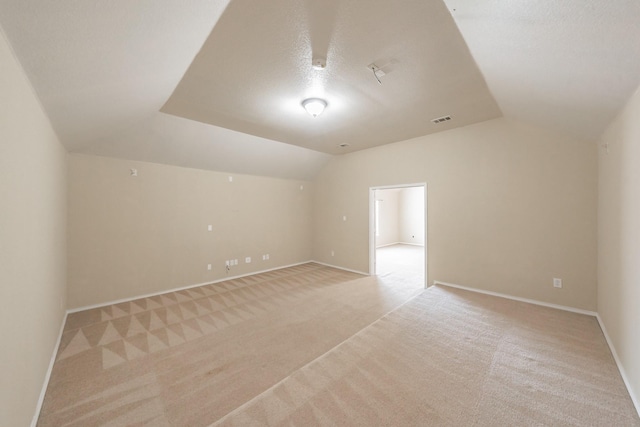 carpeted spare room with a textured ceiling and vaulted ceiling