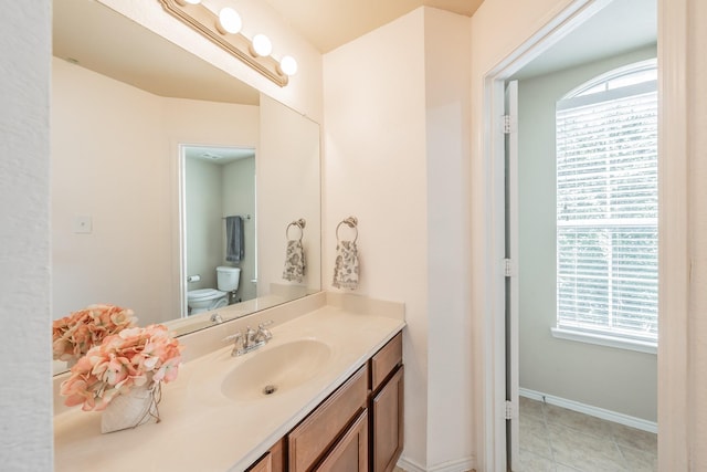 bathroom featuring tile patterned flooring, toilet, vanity, and a healthy amount of sunlight