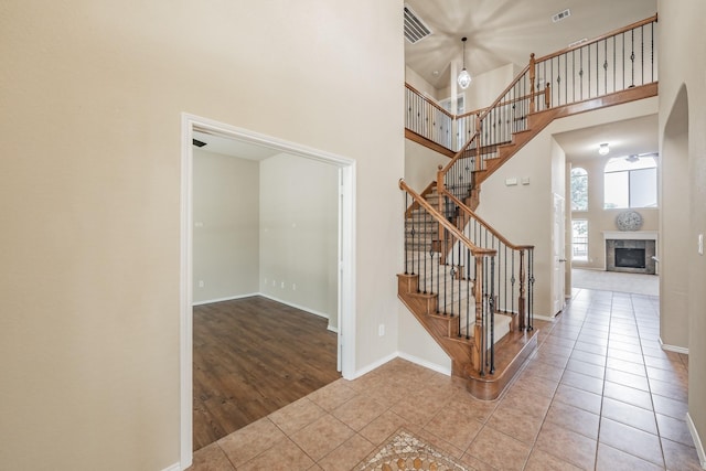 staircase featuring a tiled fireplace, a high ceiling, and tile patterned floors