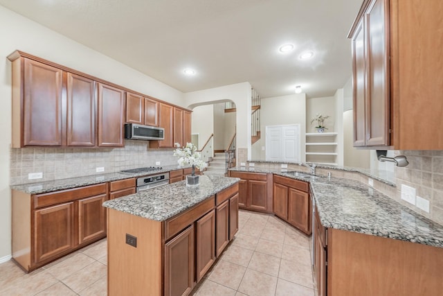 kitchen featuring kitchen peninsula, light stone counters, a kitchen island, and appliances with stainless steel finishes