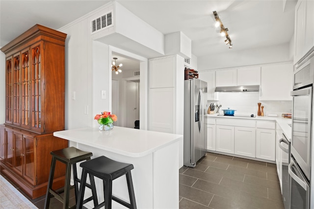 kitchen with dark tile patterned flooring, white cabinets, black electric stovetop, stainless steel fridge with ice dispenser, and a breakfast bar area