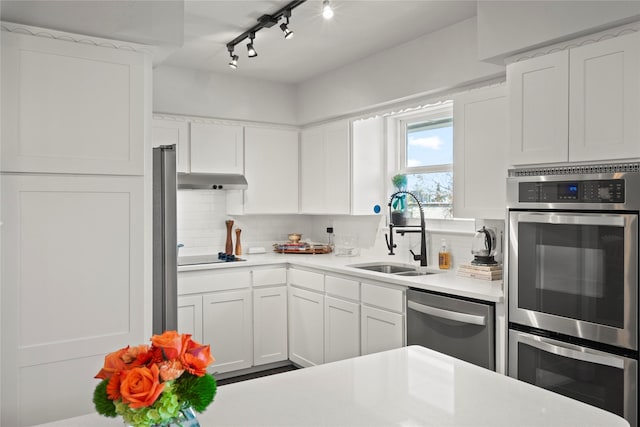 kitchen featuring appliances with stainless steel finishes, white cabinetry, decorative backsplash, sink, and rail lighting