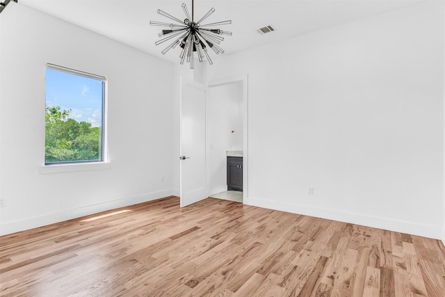 spare room featuring light hardwood / wood-style floors and an inviting chandelier