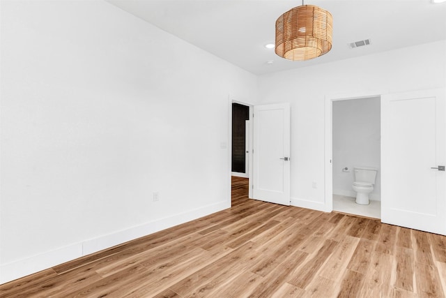 unfurnished bedroom featuring light hardwood / wood-style floors and connected bathroom