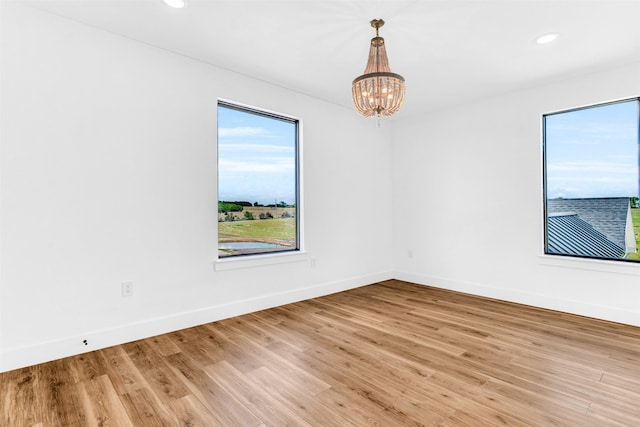 spare room with light wood-type flooring and a notable chandelier