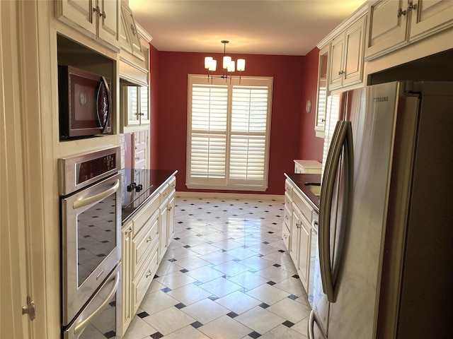 kitchen with cream cabinets, a notable chandelier, hanging light fixtures, and stainless steel refrigerator