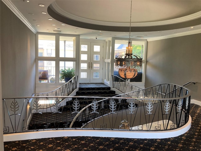 stairway with a tray ceiling and crown molding