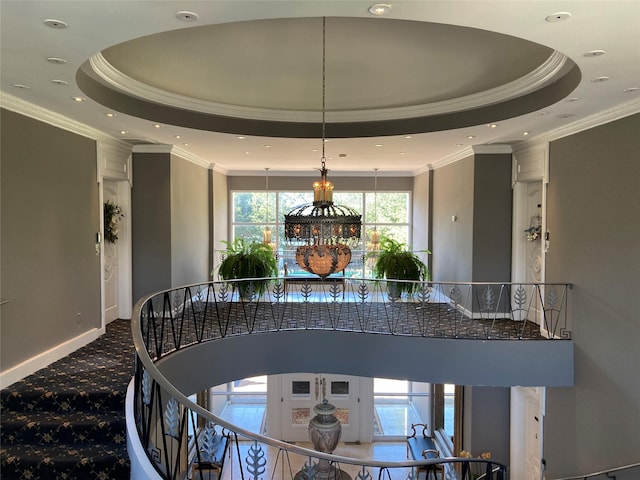 stairway with crown molding and a raised ceiling