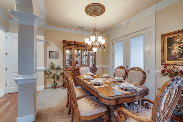 carpeted dining room featuring ornate columns, a notable chandelier, crown molding, and french doors