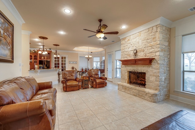 living room with a healthy amount of sunlight, crown molding, a stone fireplace, and light tile patterned flooring