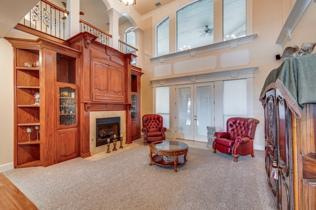 carpeted living room with ornate columns, a fireplace, ceiling fan, crown molding, and french doors