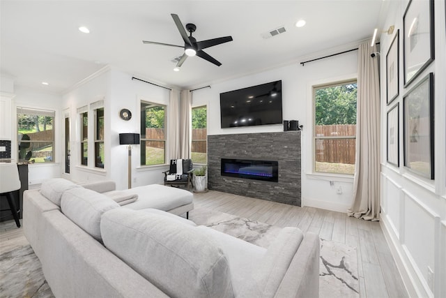 living room featuring a fireplace, light wood-type flooring, a wealth of natural light, and ornamental molding