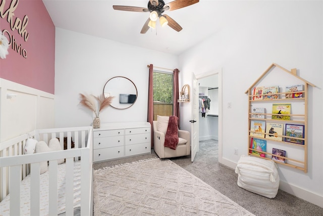 carpeted bedroom with ceiling fan and a crib