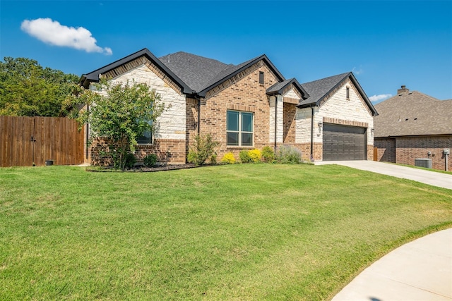 view of front of house with a front yard, central AC unit, and a garage