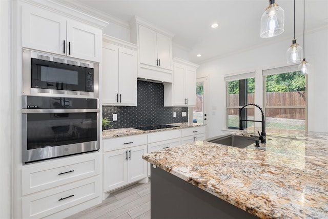 kitchen with built in microwave, sink, white cabinetry, light stone countertops, and stainless steel oven