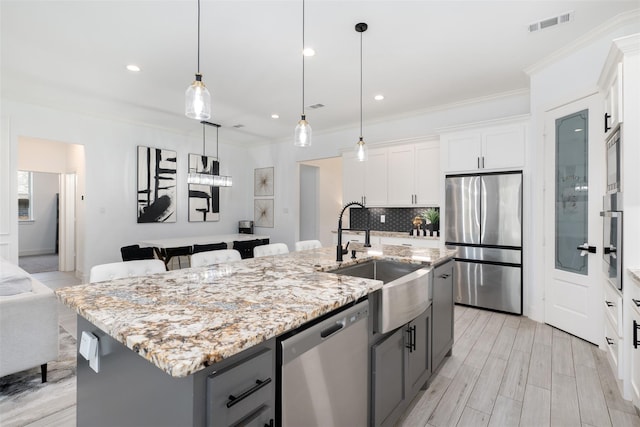 kitchen with gray cabinets, white cabinetry, a center island with sink, and appliances with stainless steel finishes