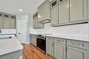 kitchen featuring light hardwood / wood-style floors, premium range hood, gray cabinetry, and stainless steel range with electric cooktop