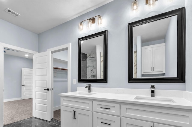 bathroom featuring double vanity, a spacious closet, visible vents, and a sink