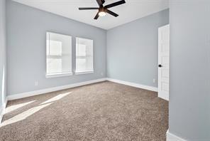 spare room with ceiling fan and dark colored carpet