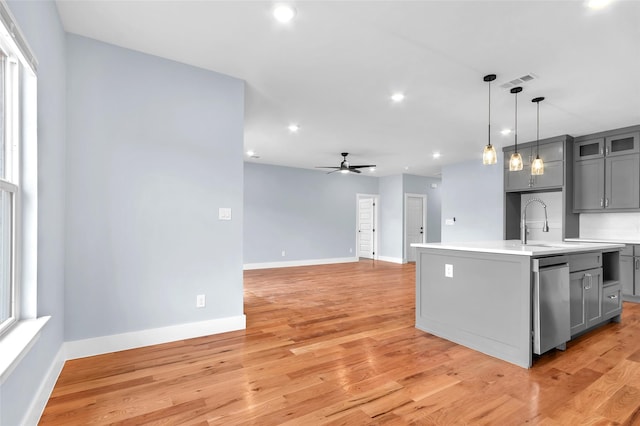 kitchen featuring gray cabinetry, visible vents, light countertops, stainless steel dishwasher, and light wood finished floors