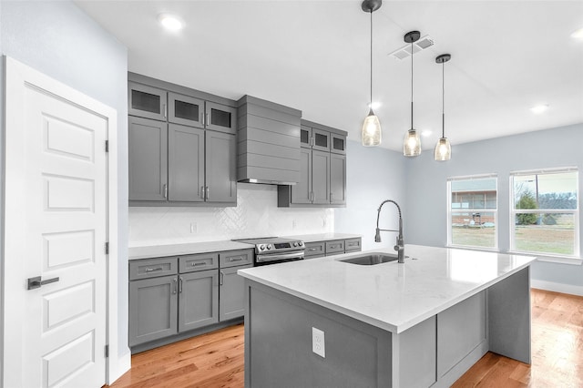 kitchen with gray cabinets, light wood-style flooring, decorative backsplash, stainless steel range with electric cooktop, and a sink