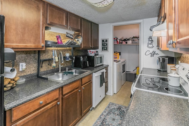 kitchen featuring white dishwasher, sink, washing machine and clothes dryer, a textured ceiling, and range