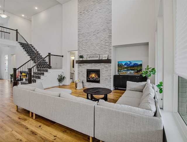 living room with a high ceiling, wood-type flooring, and a stone fireplace