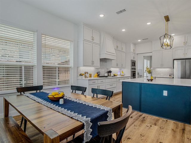 kitchen featuring white cabinetry, premium range hood, pendant lighting, and stainless steel appliances