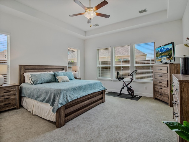 carpeted bedroom with ceiling fan and a raised ceiling