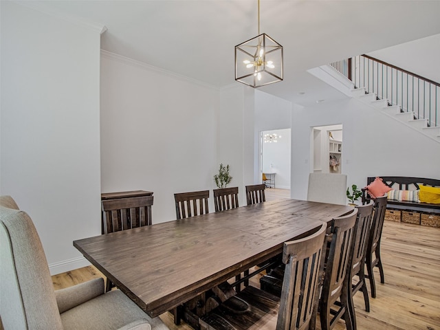 dining room with light hardwood / wood-style flooring, ornamental molding, and a notable chandelier